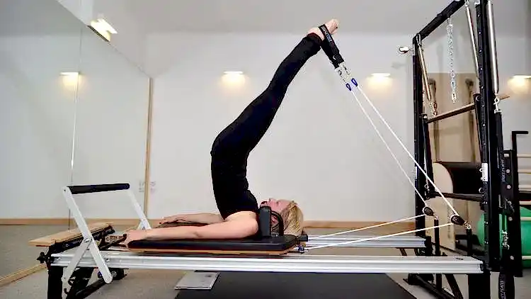 Reformer pilates aleti üzerinde egzersiz yapan kadın